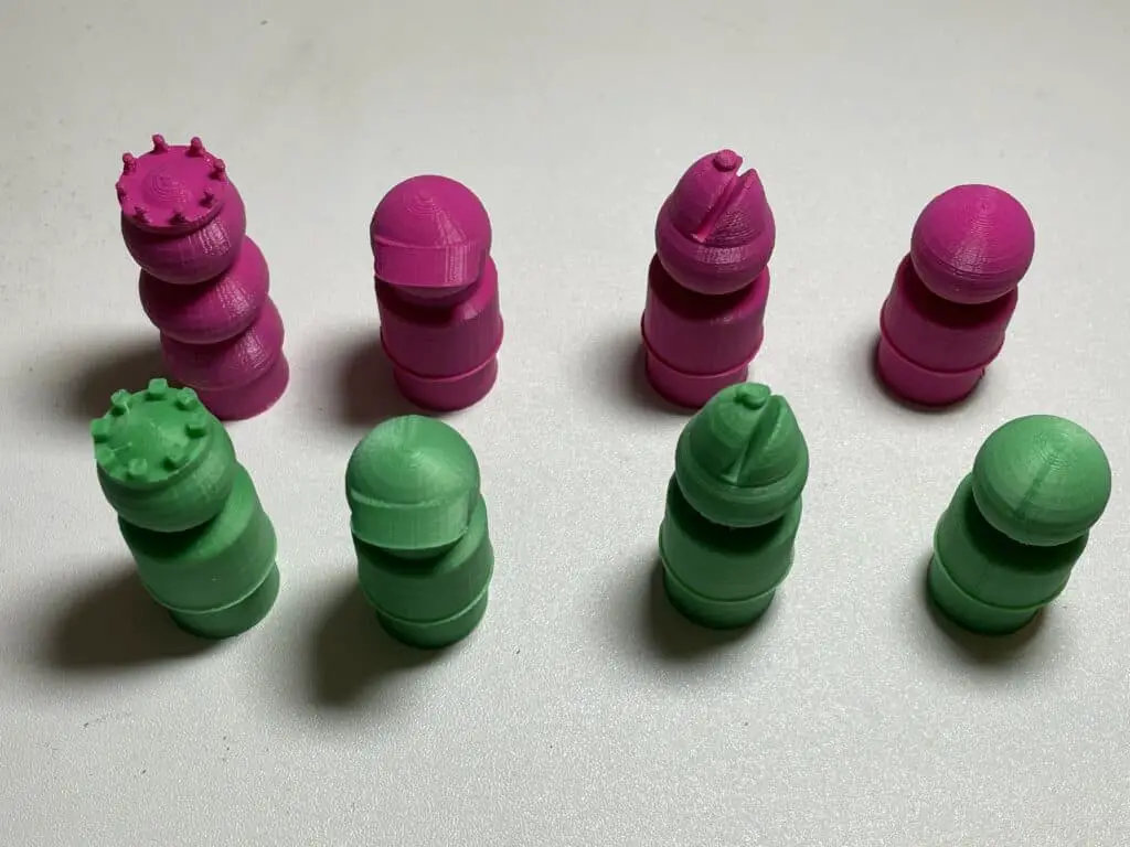 An array of chess pieces. Two rows: The top row has 4 pink pieces, the second row has 4 pink pieces. The first column both have crowns. The second column both have visors or caps. The third column both have pointy heads with a slit. The fourth column both have round heads.