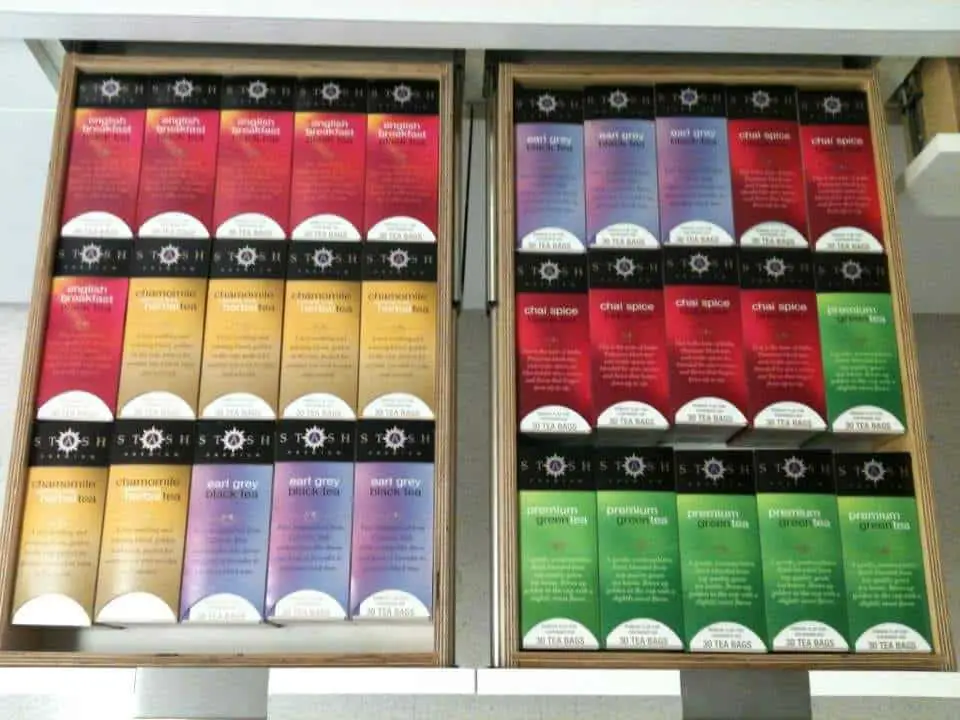 Two open drawers containing boxes of Stash-brand tea bags. Each drawer is arranged in 3 rows of 5 boxes which fit almost perfectly in the drawers. There are 5 types of tea, with 6 boxes of each type. They are lined up by type left-to-right, top-to-bottom, filling the first drawer and then the second drawer. Since there are too many boxes of each type to fit in just one row in a drawer, each type "spills over" into the next row.